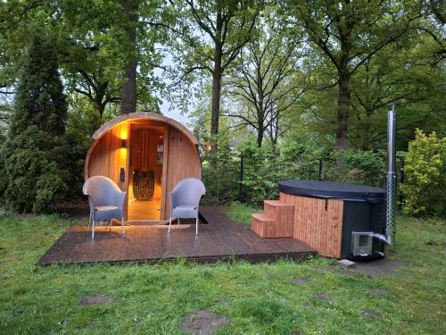 a small wooden house with two chairs and a grill at La casa Pacha Mama Sauna en Hottub in Ewijk