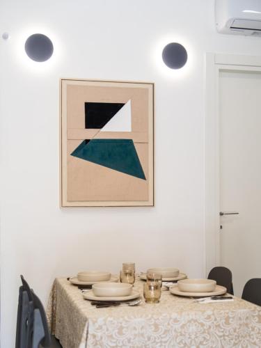 a table with plates and glasses on it with a picture on the wall at Pellarhome Quality Guest House in Pellaro