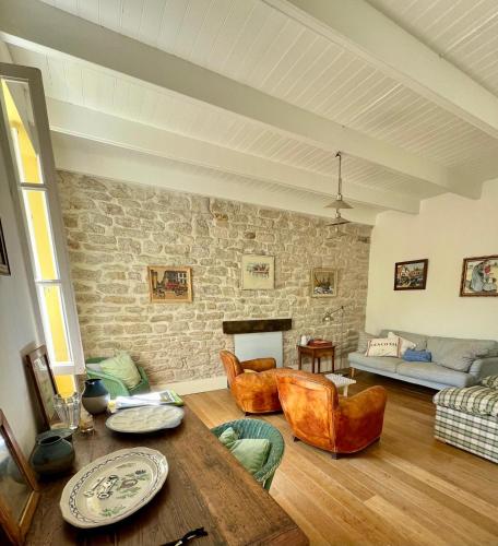 un salon avec une table et un mur en pierre dans l'établissement Maison des Dunes, à Plobannalec-Lesconil