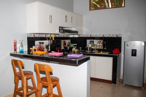 a kitchen with a counter with two chairs and a refrigerator at Amasisa Casa Vacacional Sauce, Laguna Azul in Sauce
