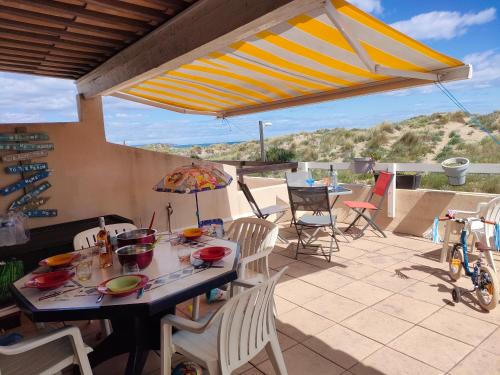 un patio avec une table, des chaises et un parasol dans l'établissement Abri Côtier, au Cap d'Agde
