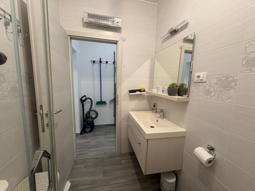 a white bathroom with a sink and a mirror at Apartmani RiA in Punat