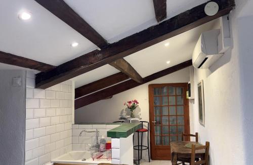 Il comprend une cuisine avec des murs blancs et des poutres apparentes. dans l'établissement Garibaldi mansardé, à Nice