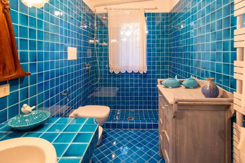 a blue tiled bathroom with a toilet and a sink at Exclusive Villa in Porto Rotondo with jacuzzipool in Porto Rotondo