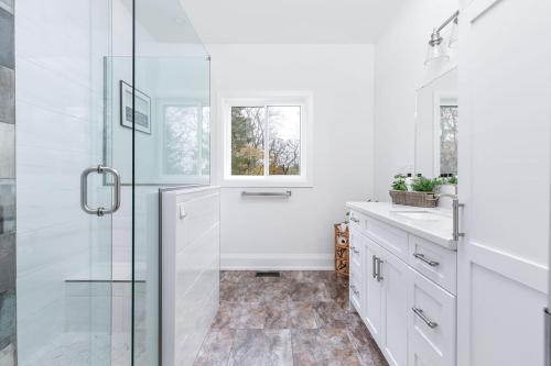une salle de bain blanche avec une douche et un lavabo dans l'établissement All Season Muskoka Cottage, à Huntsville