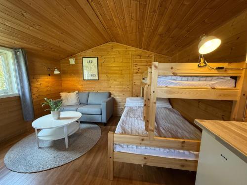 a room with a bunk bed and a couch in a cabin at Cozy Camping Cabin in Hjelmeland