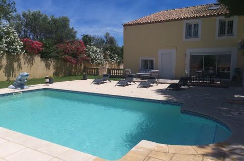 une piscine avec des chaises et une maison dans l'établissement Logement cosy avec piscine et jacuzzi privé, à Poussan