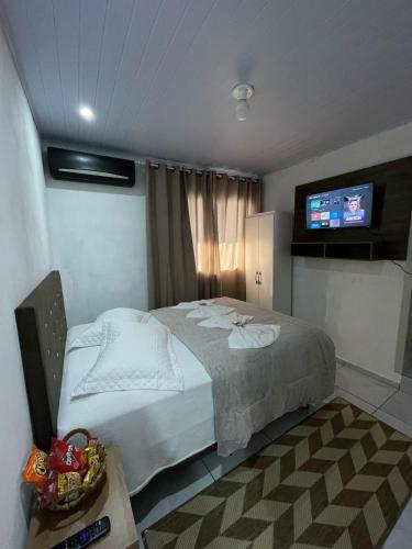 a bedroom with a bed and a flat screen tv at Pousada Quartos da Serra in Louro Müller