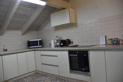 a kitchen with white cabinets and a microwave at הזהר הצפוני in Rosh Pinna