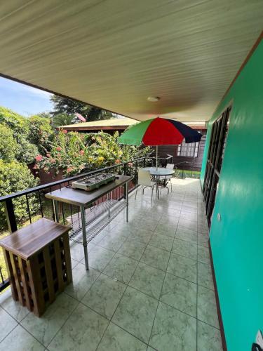 a patio with a red and green umbrella and tables at Playa Negra Zen Bistro in Puerto Limón