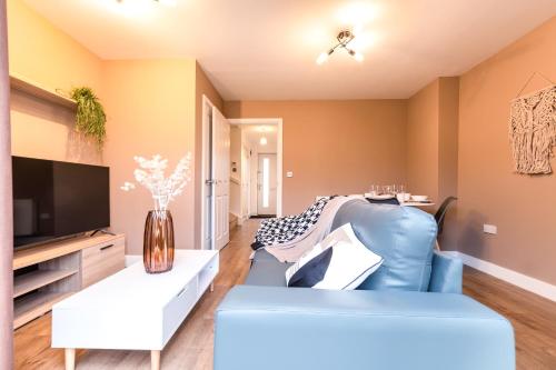 a living room with a blue couch and a tv at Stylish Modern Stay Prime Location Free Parking & Fast Wi-Fi in Peterborough