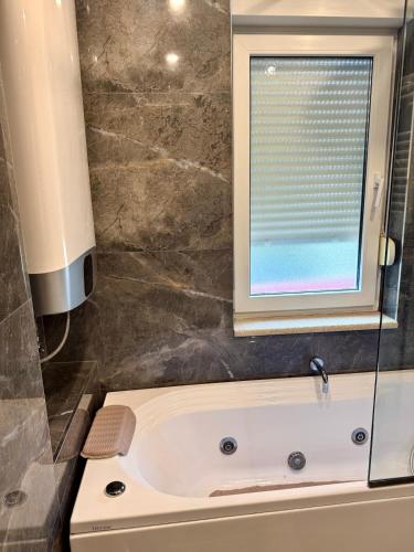 a bathroom with a bath tub with a window at Tirana Lake Spacious Apartment in Sauk
