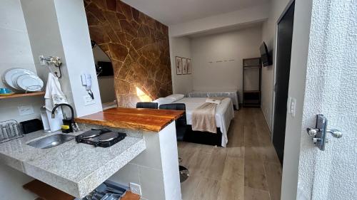 a kitchen with a sink and a bed in a room at Aconchego BH in Belo Horizonte