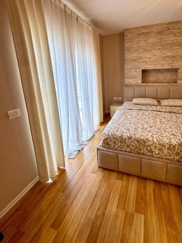 a bedroom with a bed and a large window at Tirana Lake Spacious Apartment in Sauk