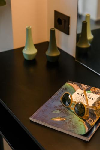 a table with a book and three vases on it at X luxury suites in Argostoli