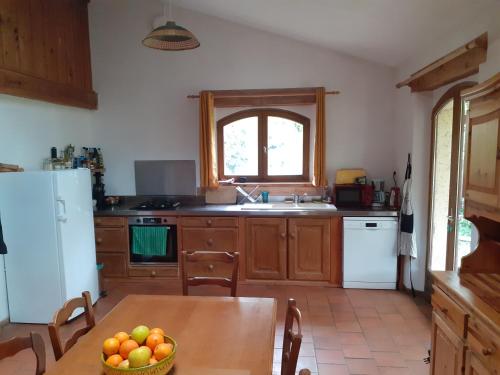 une cuisine avec une table et un réfrigérateur blanc dans l'établissement Gîte à la ferme, à Montolieu