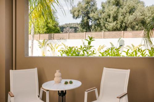 two white chairs and a table and a window at X luxury suites in Argostoli