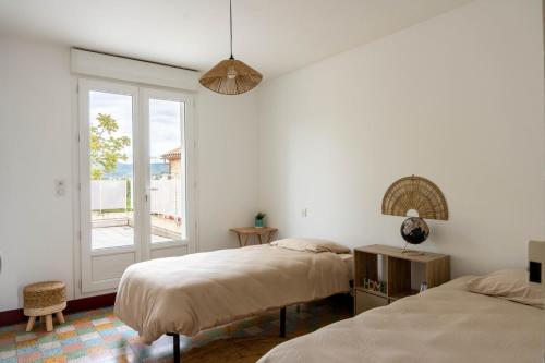 deux lits dans une chambre blanche avec une fenêtre dans l'établissement Villa Léa Alès 5 chambres, à Alès
