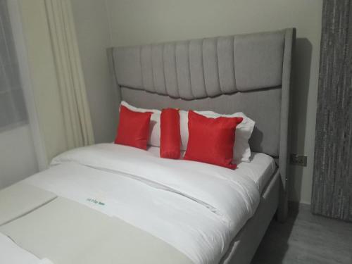 a white bed with four red pillows on it at Staycation by Winnie-Weber Generations -2 bedrooms in Nairobi