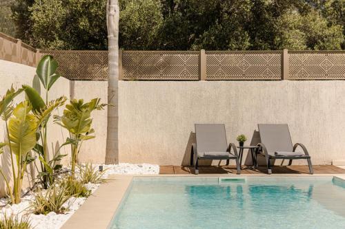 two chairs and a table next to a swimming pool at X luxury suites in Argostoli