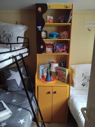a bedroom with a bunk bed and a yellow nightstand next to a bunk bed at Mobil home LE COUCOU in Le Martinet