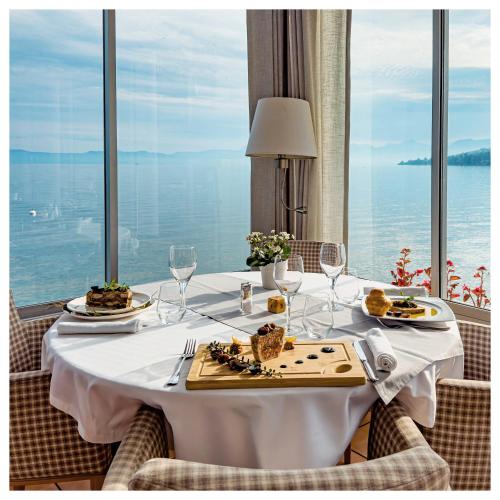 une table avec des assiettes de nourriture sur une table avec des fenêtres dans l'établissement Hôtel De La Plage, à Amphion-les-Bains
