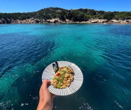 a person holding a plate of food on the water at Principessa dei draghi Full Day and Night Experience in Izola