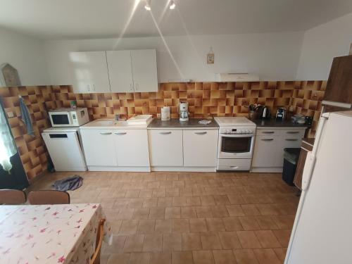 une cuisine avec des armoires blanches et des appareils électroménagers blancs dans l'établissement Gîte des 2 Moulins, à Grand Brassac