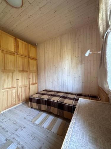 a room with a bed in a room with wooden walls at Villa Vlada in Gāršmuiža