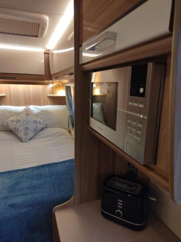 a small room with a bed and a microwave at Country Roost in High Wycombe