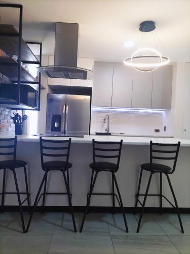 a kitchen with four chairs and a counter with a sink at Loft SB in Aguascalientes