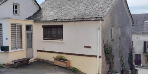 une maison blanche avec un banc devant dans l'établissement Maison village en Aveyron, à Durenque
