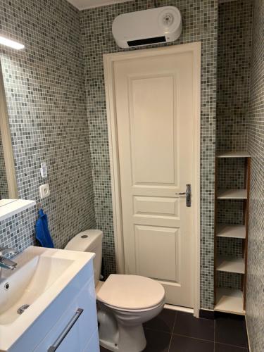 La salle de bains est pourvue de toilettes et d'une porte blanche. dans l'établissement Magnifique 2 pièces, à Nice