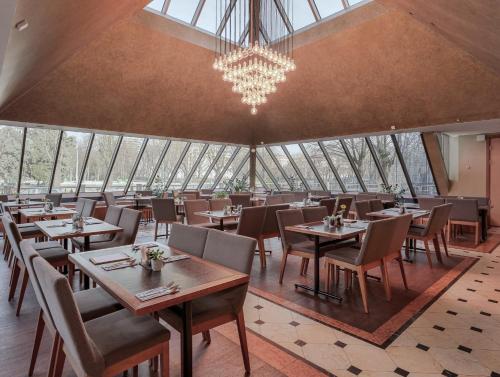 a restaurant with tables and chairs and a chandelier at Radisson Blu Ridzene Hotel, Riga in Rīga