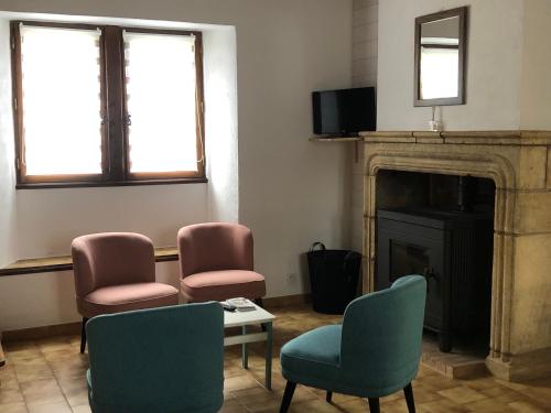 - un salon avec trois chaises et une cheminée dans l'établissement Gîte Le Colombet, à Audrix