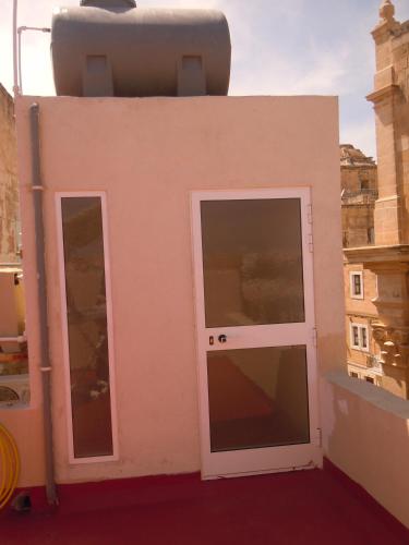 ein kleines rosafarbenes Gebäude mit einer Tür und Fenstern in der Unterkunft Number 12 in Vittoriosa
