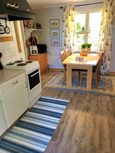 a kitchen with a table and a white stove top oven at Linnåsen stuga in Rottneros