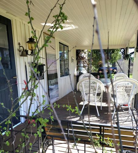 a porch with white wicker chairs and a table at Linnåsen stuga in Rottneros