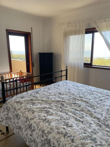 a bedroom with a large bed and two windows at Carminho beach house in Vila do Conde