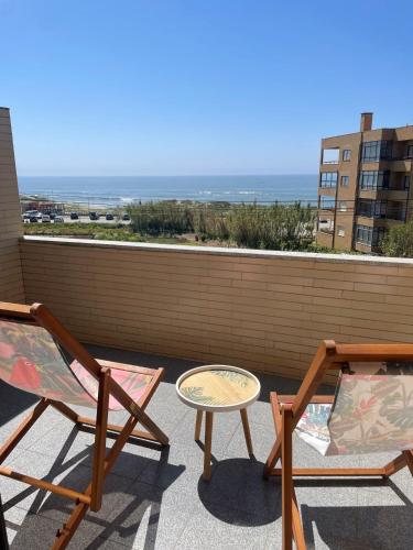 two chairs and a table on a balcony with the ocean at Carminho beach house in Vila do Conde