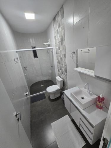 a white bathroom with a shower and a sink at Aconchego da Família de Oliveira in Camboriú