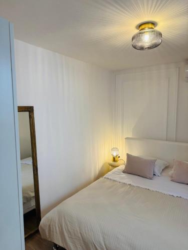 a bedroom with a white bed and a mirror at Apartment Stari Dvor in Kaštela
