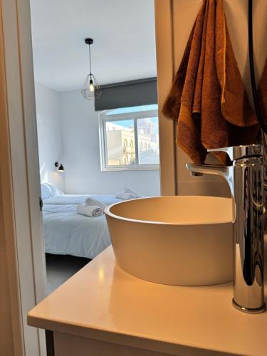 a bathroom with a sink and a bed in a room at Brand new Gozo escape - Ir-Ramla Apartment, Nadur in Nadur