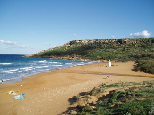 a view of a beach with a lighthouse and the ocean at Brand new Gozo escape - Ir-Ramla Apartment, Nadur in Nadur