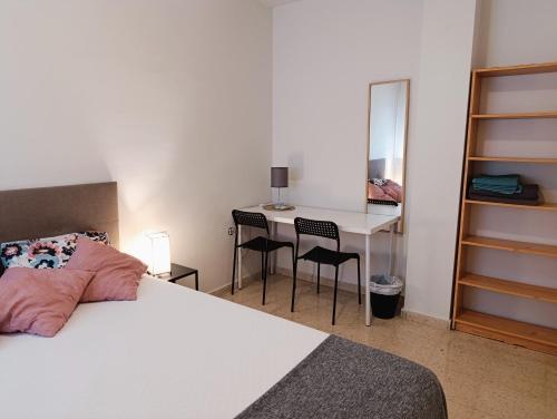a bedroom with a bed and a desk with chairs at Habitación doble ALAMEDA CENTRO MACARENA in Seville