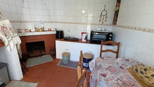 a small kitchen with a table and a microwave at Orion Guesthouse Telhado in Fundão