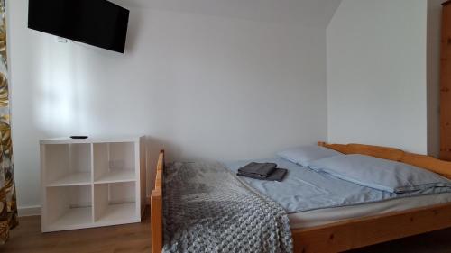 a bedroom with a bed and a tv on a wall at Liść Klonu in Polańczyk
