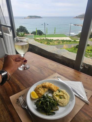a plate of food on a table with a glass of wine at Poseidon Apartments and Villas by the Sea in Sounio