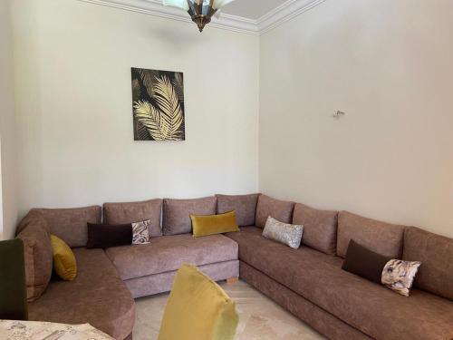 a living room with a brown couch and a painting at CASABAY Sidi Rahal, appartement avec accès direct à la piscine in Sidi Rahal