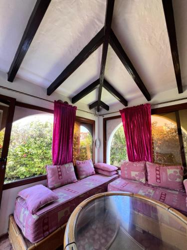 a train car with pink pillows and a glass table at Mini-Villa à deux pas de la plage in Cabo Negro